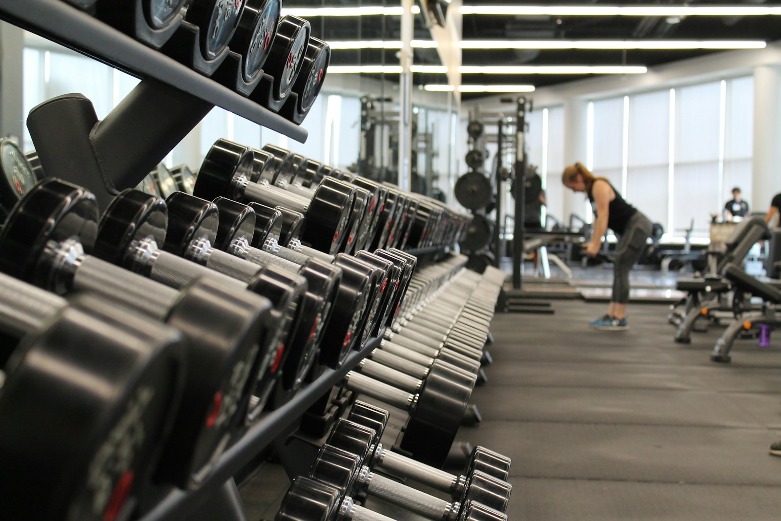 Rack de mancuernas y persona entrenando en un gimnasio con control de acceso biométrico RoxifyDesk